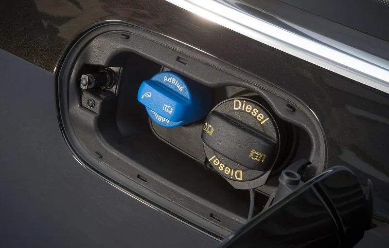 Blue AdBlue filler cap beside the diesel cap in a car's fuel flap