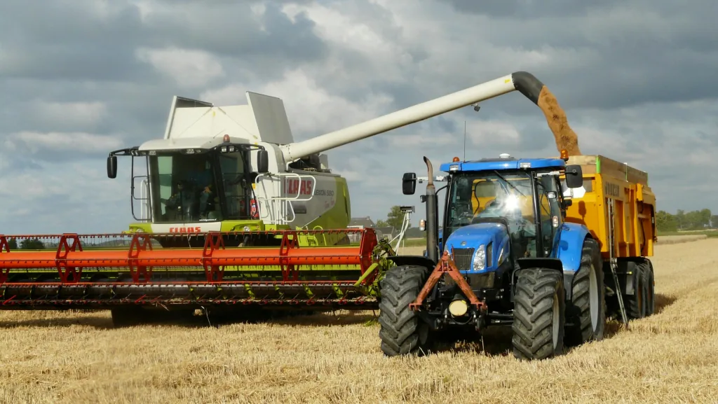 Combine harvester unloading grain into a trailer towed by a tractor
